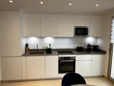 a kitchen with white cabinets and a sink and a microwave at Elegant apartment close to Croisette and Palais de Festival with garage in Cannes
