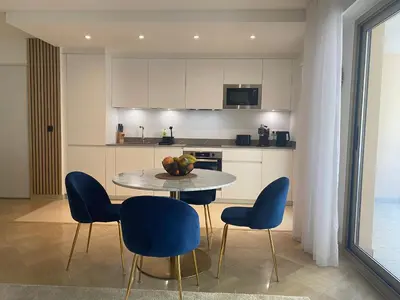 a kitchen with a table and four chairs and a kitchen with white cabinets at Elegant apartment close to Croisette and Palais de Festival with garage in Cannes