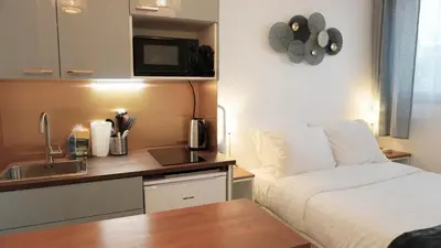 a bedroom with a bed and a kitchen with a sink at Proche Croisette, Studio moderne by Palmazur Vacances in Cannes