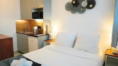 a bedroom with a white bed and a kitchen at Proche Croisette, Studio moderne by Palmazur Vacances in Cannes