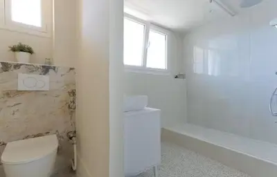 a white bathroom with a toilet and a bath tub at LE ROCHER avec terrasse et vue mer, près du centre-ville in Cannes