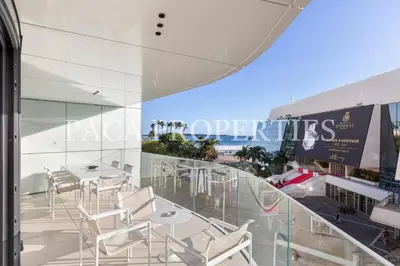 a balcony with white chairs and tables and a building at Paca Properties -401- 5 Chambres Luxe in Cannes