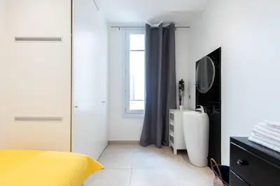 a white bedroom with a yellow bed and a television at LE SINATRA splendide vue mer panoramique et balcon, idéal pour des séjours de loisirs ou business in Cannes