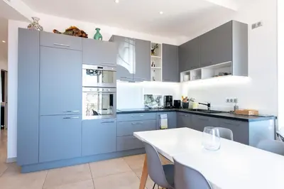 a kitchen with blue cabinets and a white table at LE SINATRA splendide vue mer panoramique et balcon, idéal pour des séjours de loisirs ou business in Cannes