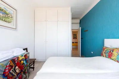a bedroom with a white bed and a blue wall at LE SINATRA splendide vue mer panoramique et balcon, idéal pour des séjours de loisirs ou business in Cannes