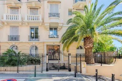 a palm tree in front of a building at LE SINATRA splendide vue mer panoramique et balcon, idéal pour des séjours de loisirs ou business in Cannes