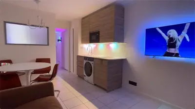 a living room with a kitchen and a tv on a wall at EXCEPTIONNEL sur CANNES vue mer piscine in Cannes