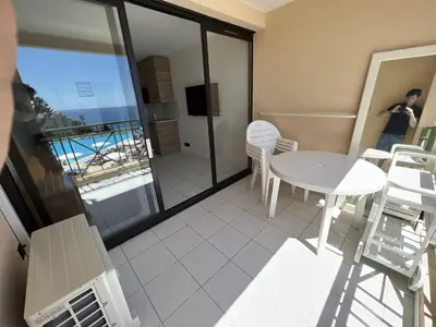 a room with a table and chairs and a balcony at EXCEPTIONNEL sur CANNES vue mer piscine in Cannes