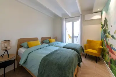 a bedroom with a bed and a yellow chair at Renovated bijou gem in heart of Cannes in Cannes