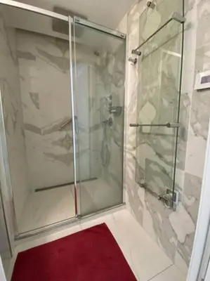 a bathroom with a glass shower with a red rug at PACA Properties 7C2 - appartement 3 chambres in Cannes