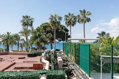 a view of a park with palm trees and the ocean at Cannes: Croisette Quartier Martinez - 90m² in Cannes