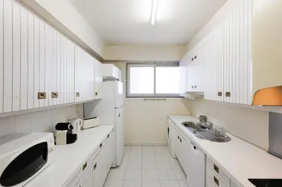 a kitchen with white cabinets and a sink and a window at Cannes: Croisette Quartier Martinez - 90m² in Cannes