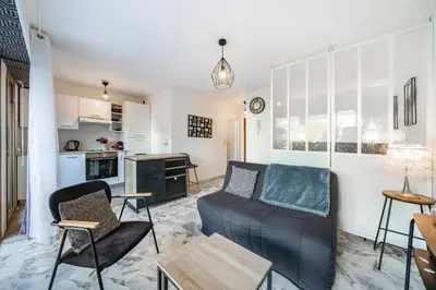 a living room with a couch and a kitchen at Studio avec terrasse et jardin arboré - 5 min hypercentre Cannes in Cannes