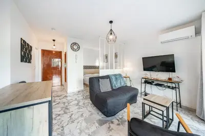 a living room with a couch and a tv at Studio avec terrasse et jardin arboré - 5 min hypercentre Cannes in Cannes