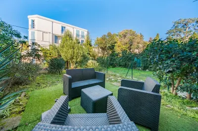 a garden with two chairs and a table and a building at Studio avec terrasse et jardin arboré - 5 min hypercentre Cannes in Cannes