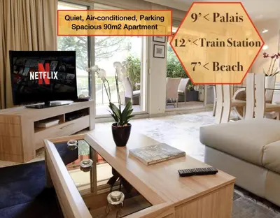 a living room with a couch and a table and a tv at 90m2 Apartement - Les Palmiers de Cannes in Cannes