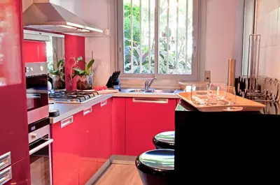 a kitchen with red cabinets and a sink and a window at 90m2 Apartement - Les Palmiers de Cannes in Cannes