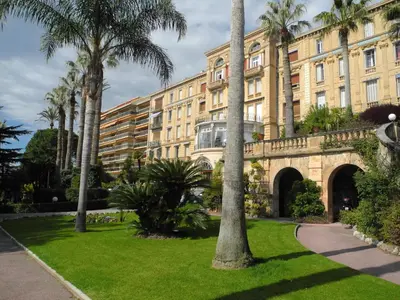a building with palm trees in front of a park at 90m2 Apartement - Les Palmiers de Cannes in Cannes