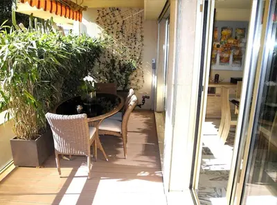 a patio with a table and chairs and plants at 90m2 Apartement - Les Palmiers de Cannes in Cannes
