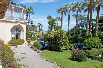 a driveway in front of a house with palm trees at 90m2 Apartement - Les Palmiers de Cannes in Cannes