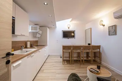 a kitchen with white cabinets and a table at MEY T2 - Superbe appartement 4 pers, 50m du vieux port et 2min à pied du palais in Cannes