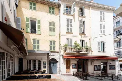 a building with green shutters and tables in a street at MEY T2 - Superbe appartement 4 pers, 50m du vieux port et 2min à pied du palais in Cannes