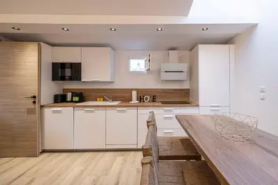 a kitchen with white cabinets and a wooden table at MEY T2 - Superbe appartement 4 pers, 50m du vieux port et 2min à pied du palais in Cannes