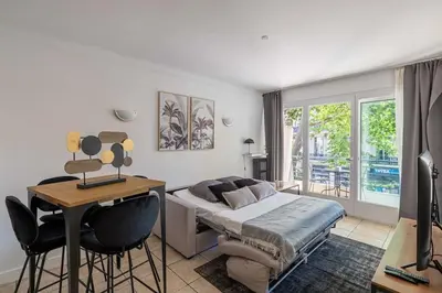 a bedroom with a bed and a table and chairs at 29 CARNOT - Chaleureux appartement avec balcon - centre ville in Cannes