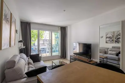 a living room with a couch and a table at 29 CARNOT - Chaleureux appartement avec balcon - centre ville in Cannes