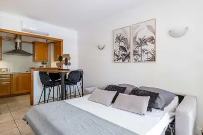 a bedroom with a bed and a kitchen with a table at 29 CARNOT - Chaleureux appartement avec balcon - centre ville in Cannes