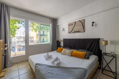 a bedroom with a large bed and a window at 29 CARNOT - Chaleureux appartement avec balcon - centre ville in Cannes