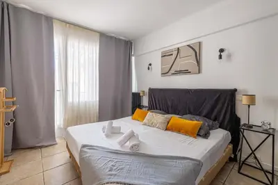 a bedroom with a large bed with yellow and gray pillows at 29 CARNOT - Chaleureux appartement avec balcon - centre ville in Cannes