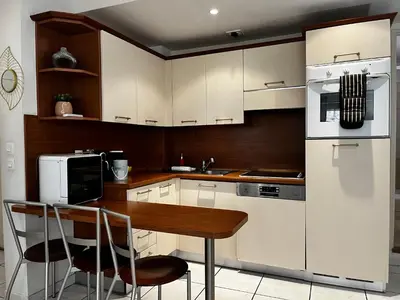 a kitchen with white cabinets and a wooden table at Cannes en plein cœur in Cannes