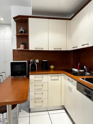 a kitchen with white cabinets and a wooden table at Cannes en plein cœur in Cannes