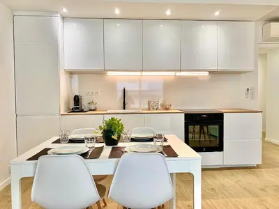 a white kitchen with a white table and chairs at Appartement Cannes 2 chambres - 14J in Cannes