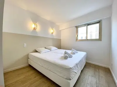 a bedroom with a bed with white sheets and a window at Appartement Cannes 2 chambres - 14J in Cannes