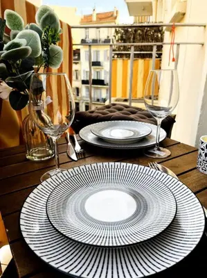 a wooden table with plates and wine glasses on it at Cosy Studio - Plage et Suquet in Cannes