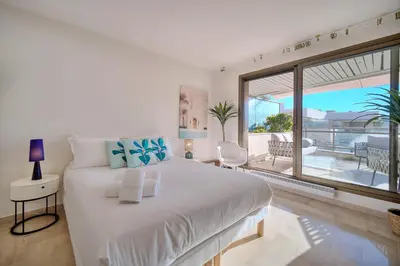 a white bedroom with a large bed and a balcony at REF 1174 - Apartment with Sea View in Cannes