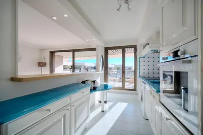 a kitchen with white cabinets and blue counter tops at REF 1174 - Apartment with Sea View in Cannes