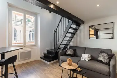 a living room with a couch and a staircase at 3 LEGOF - Charmant appartement 4 couchages centre Cannes in Cannes