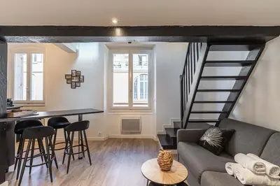 a living room with a couch and a spiral staircase at 3 LEGOF - Charmant appartement 4 couchages centre Cannes in Cannes