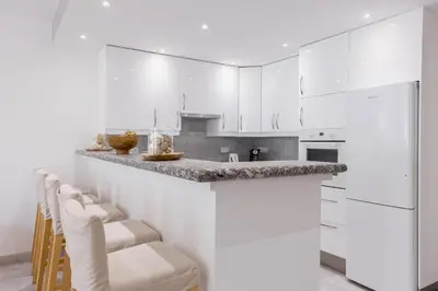 a kitchen with white cabinets and a bar with stools at 38 Meynadier 4p by Halldis in Cannes