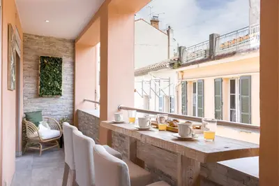 a balcony with a table and chairs and a window at 38 Meynadier 4p by Halldis in Cannes