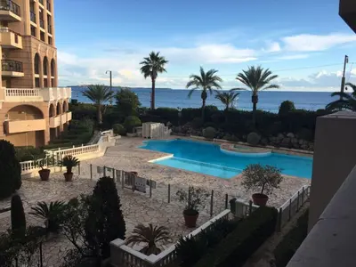 a view of a swimming pool with palm trees and the ocean at Appartement 531 in Cannes