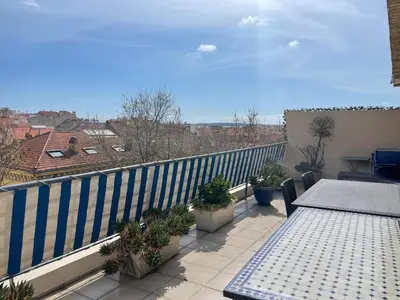 a balcony with a table and a blue fence at Toit terrasse proche plages Croisette et Palais des Festivals in Cannes
