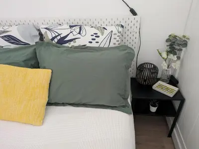 a bed with four pillows on it with a side table at Cannes Isola Bella entre mer et montagne in Cannes