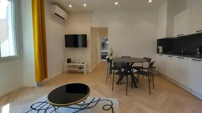 a living room with a table and chairs and a kitchen at Lovely apartment heart of Cannes in Cannes