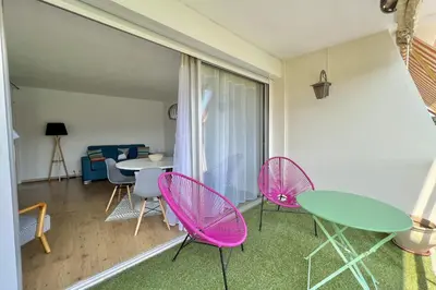 a living room with pink chairs and a table at Bright studio just outside Cannes in Le Cannet