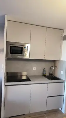 a kitchen with white cabinets and a microwave at Résidence Pierre et Vacance 631 in Cannes