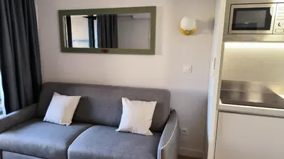 a gray couch with two pillows in a room at Résidence Pierre et Vacance 631 in Cannes